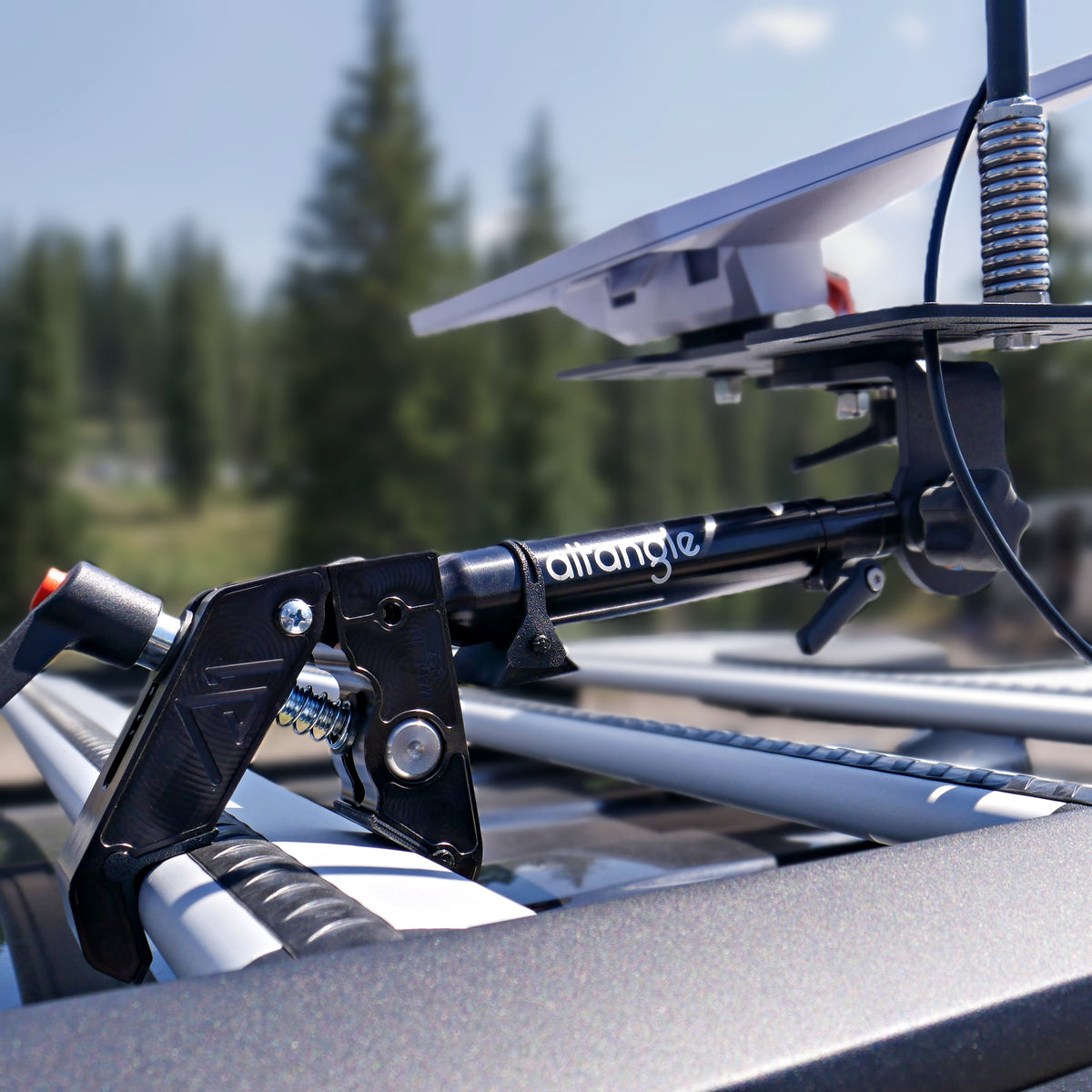 Close-up of an Altangle Connect clamp gripping a roof-rack crossbar with a Starlink Mini mounted on the pole mount plate above