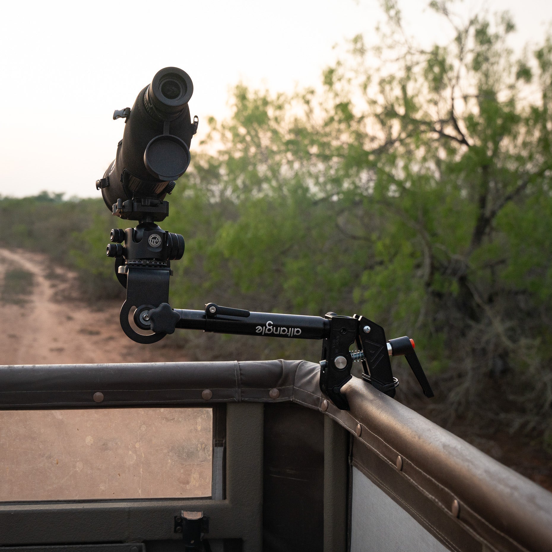 Connect Hub clamped to a padded vehicle rail holding a spotting scope over brush country