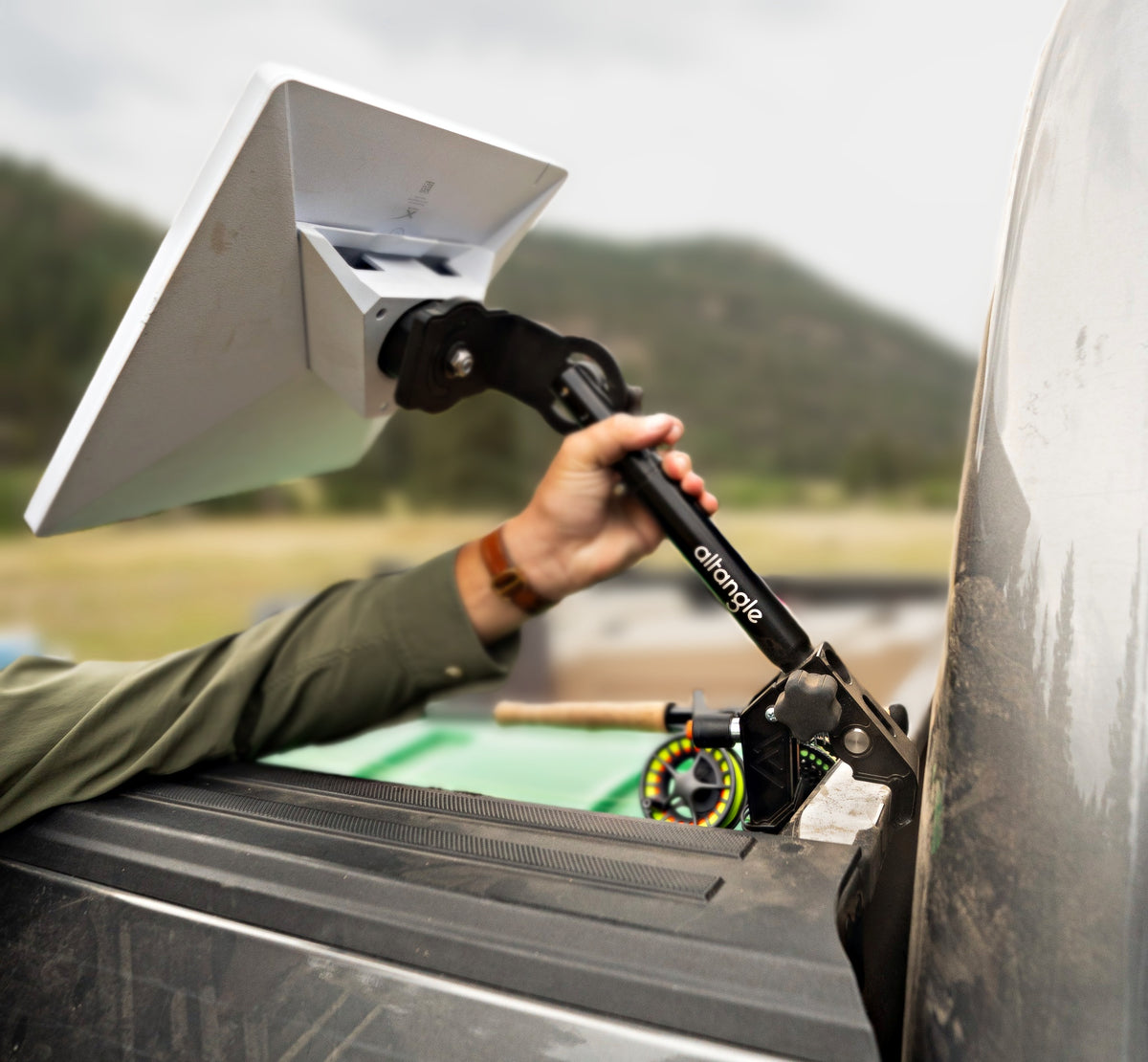 Hand adjusting the telescoping bar of an Altangle Connect mount holding a Starlink Mini above a pickup bed rail
